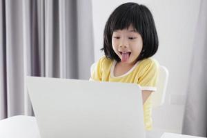 poco asiatico ragazza alunno studia in linea utilizzando il computer portatile computer a casa foto