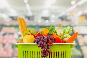 carrello pieno di frutta e verdura con supermercato negozio di alimentari sfocato sfondo sfocato con luce bokeh foto