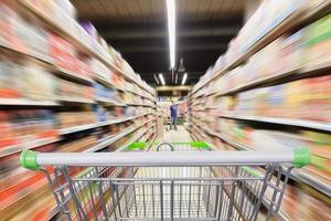 Sfocatura movimento del corridoio del supermercato con carrello vuoto foto