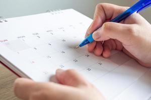 donna mano con penna scrittura su calendario Data attività commerciale pianificazione appuntamento incontro concetto foto