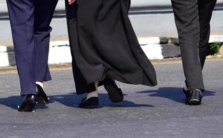 vicino su di donna di piedi a passeggio. donna nel lungo gonna e nero scarpe a piedi foto