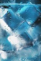 bicchiere con acqua e ghiaccio cubi su un' blu sfondo foto