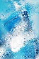 bicchiere con acqua e ghiaccio cubi su un' blu sfondo foto