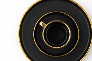 un' impostato di nero e d'oro ceramica piatti e tazza su un' bianca sfondo superiore Visualizza foto