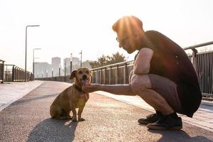giovane bello uomo è a piedi con il suo cane nel il mattina su vuoto strada di città. foto