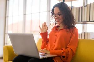 donna latina che lavora con il laptop sul divano foto