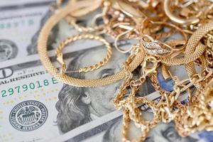 molti costoso d'oro jewerly anelli, orecchini e collane con grande quantità di noi dollaro fatture su bianca sfondo. banco dei pegni o jewerly negozio foto