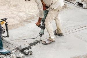 costruzione lavoratore utilizzando martello pneumatico perforazione calcestruzzo superficie foto