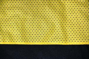 giallo sport capi di abbigliamento tessuto struttura sfondo. superiore Visualizza di giallo stoffa tessile superficie. luminosa pallacanestro camicia. testo spazio foto