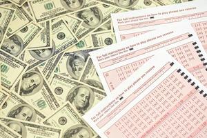 rosa gioco d'azzardo lenzuola con numeri per marcatura su grande quantità di centinaio dollaro fatture. lotteria giocando concetto o gioco d'azzardo dipendenza. vicino su foto