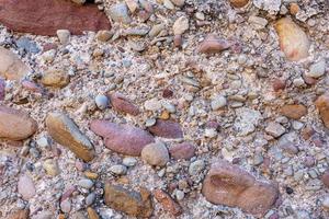 astratto struttura di diverso dimensione pietre nel un' pezzo di calcestruzzo foto