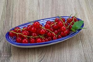 rosso ribes nel un' ciotola su di legno sfondo foto