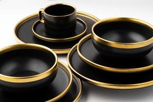un' impostato di nero e d'oro ceramica piatti e tazza su un' bianca sfondo foto