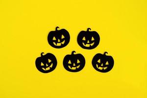 vacanza decorazioni per Halloween. cinque nero carta zucche su un' giallo sfondo, superiore Visualizza. foto
