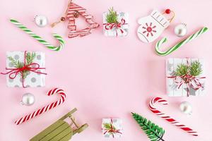 superiore Visualizza su un' telaio a partire dal rosso e verde di legno e argento Natale decorazioni, caramello bastoni e regalo scatole con abete rami su un' rosa sfondo con copia spazio. foto