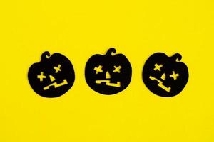 vacanza decorazioni per Halloween. tre nero carta zucche su un' giallo sfondo, superiore Visualizza. foto