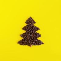 inverno composizione con Natale albero fatto di caffè fagioli e decorato cannella bastone su un' giallo sfondo, piatto posizione. saluto carta per nuovo anno con copia spazio. foto