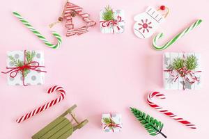 superiore Visualizza su un' telaio a partire dal rosso e verde di legno Natale decorazioni, caramello bastoni e regalo scatole con abete rami su un' rosa sfondo con copia spazio. foto