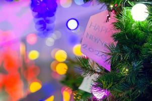 carta sospeso su Natale albero per vacanza decorazione con colorato luci su sfondo. foto