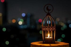 bellissimo lanterna quello avere Luna simbolo su superiore con città bokeh leggero su buio sfondo. foto