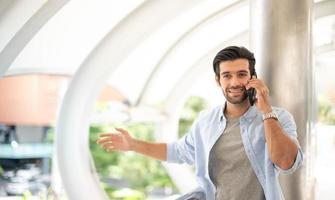 il giovane uomo utilizzando un' smartphone per parlare con il suo amico a il all'aperto. il uomo indossare casuale stoffa e sensazione contento e rilassante. foto