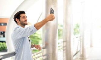 il giovane uomo autoscatto con lui stesso di il utilizzando smartphone per prendere foto, e aspettare per il suo amico. foto