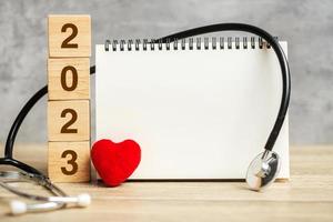 2023 felice anno nuovo per l'assistenza sanitaria, l'assicurazione, il benessere e il concetto medico. stetoscopio e taccuino vuoto per copiare lo spazio del testo foto