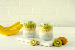 chia seme budino con kiwi, Banana e Mango. Salute disintossicazione prima colazione nel bicchieri su bianca sfondo foto