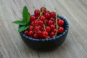 rosso ribes nel un' ciotola su di legno sfondo foto