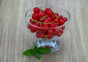 rosso ribes nel un' ciotola su di legno sfondo foto