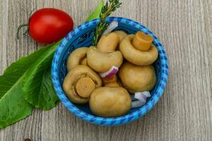 champignon sottaceto in una ciotola su fondo di legno foto