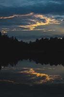 atmosferico tramonto dietro a alberi e riflessione nel acqua. foto