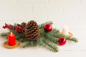 nuovo anni composizione per decorare il festivo Casa e tavolo. abete rosso rami, un' ramo con frutti di bosco, un' candela, palle e un' cono di cedro. foto