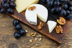 Camembert formaggio su un' di legno tavola con noccioline e fresco uva. foto