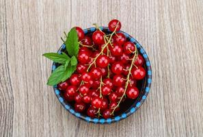 rosso ribes nel un' ciotola su di legno sfondo foto