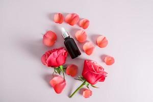 superiore Visualizza di un' cosmetico bottiglia con rosa olio, siero o un' nutriente naturale automedicazione Prodotto. un' sfondo di rosa petali. foto