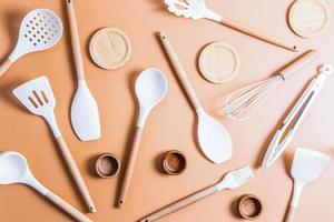 un' collezione di bianca silicone utensili per cucinando cibo nel il cucina. superiore Visualizza. piatto messa in piega. beige sfondo. foto