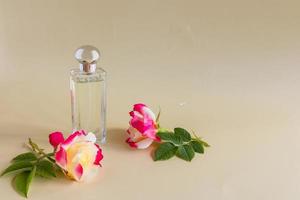 bellissimo bottiglia di Da donna profumo su un' grigio sfondo con un' elegante fiore di fragrante rosa . modello per profumo e gabinetto acqua. un' copia spazio. foto