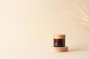 vaso di cosmetico crema con legna podio e palma foglia su pastello beige sfondo. vicino su, copia spazio foto
