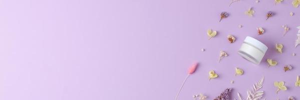 vaso di cosmetico crema con fiori su rosa sfondo. piatto posizione, copia spazio foto