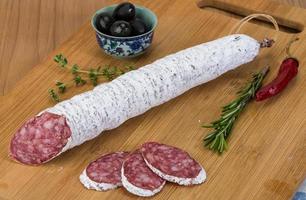 fuet salsiccia su di legno tavola e bianca sfondo foto