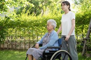 assistenza e cura del caregiver paziente asiatico anziano o anziano della donna che si siede sulla sedia a rotelle nel parco, concetto medico forte sano. foto