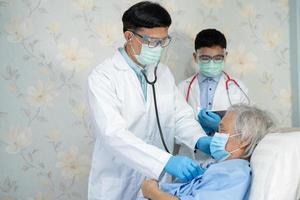 il team medico asiatico controlla il paziente anziano della signora anziana per la malattia alla motivazione nuova normalità per trattare l'infezione covid19 coronavirus nel reparto ospedaliero. foto