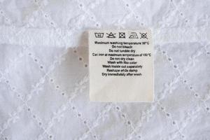 lavanderia cura lavaggio Istruzioni Abiti etichetta su tessuto struttura sfondo foto