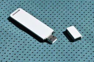 un' moderno portatile USB Wi-Fi adattatore è posto su il blu abbigliamento sportivo fatto di poliestere nylon fibra foto