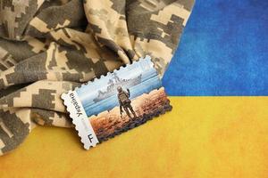 ternopil, Ucraina - settembre 2, 2022 famoso ucraino timbro postale con russo nave da guerra e ucraino soldato come di legno souvenir su esercito camuffare uniforme e nazionale bandiera foto