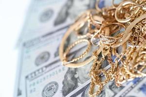 molti costoso d'oro jewerly anelli, orecchini e collane con grande quantità di noi dollaro fatture su bianca sfondo. banco dei pegni o jewerly negozio foto