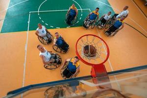 Disabilitato guerra o opera veterani misto gara e età pallacanestro squadre nel sedie a rotelle giocando un' formazione incontro nel un' gli sport Palestra sala. portatori di handicap persone reinserimento e inclusione concetto. foto