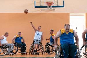 Disabilitato guerra veterani misto gara e età pallacanestro squadre nel sedie a rotelle giocando un' formazione incontro nel un' gli sport Palestra sala. portatori di handicap persone reinserimento e inclusione concetto foto