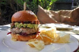 fresco hamburger con carne, pomodoro, avocado, formaggio, rosso cavolo, salamoia e patatine fritte. foto